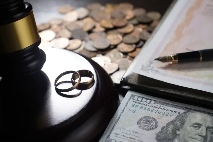 Wedding rings and gavel with money and legal document conveying theme of divorce