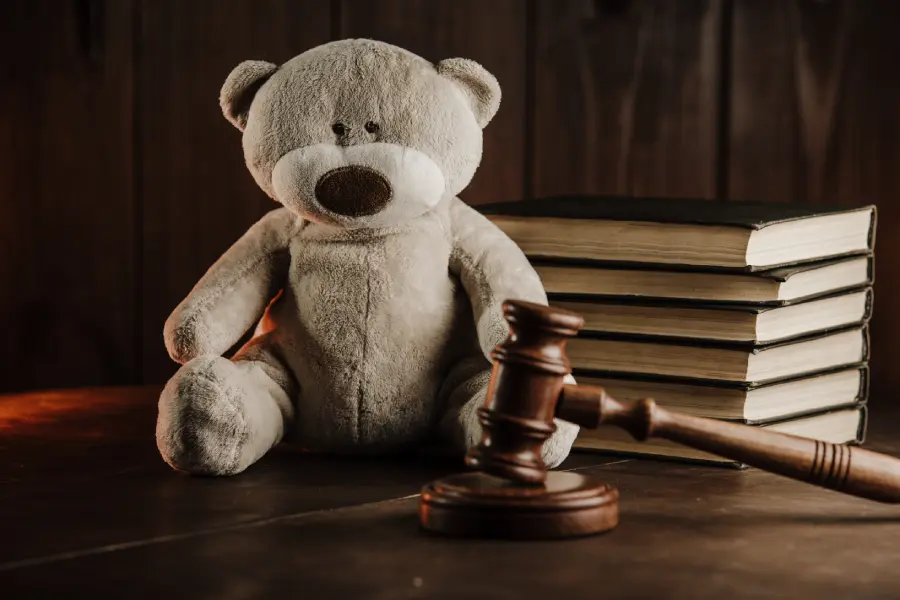Downloaded Divorce and alimony concept. Wooden gavel and teddy bear as symbol of child on a desk