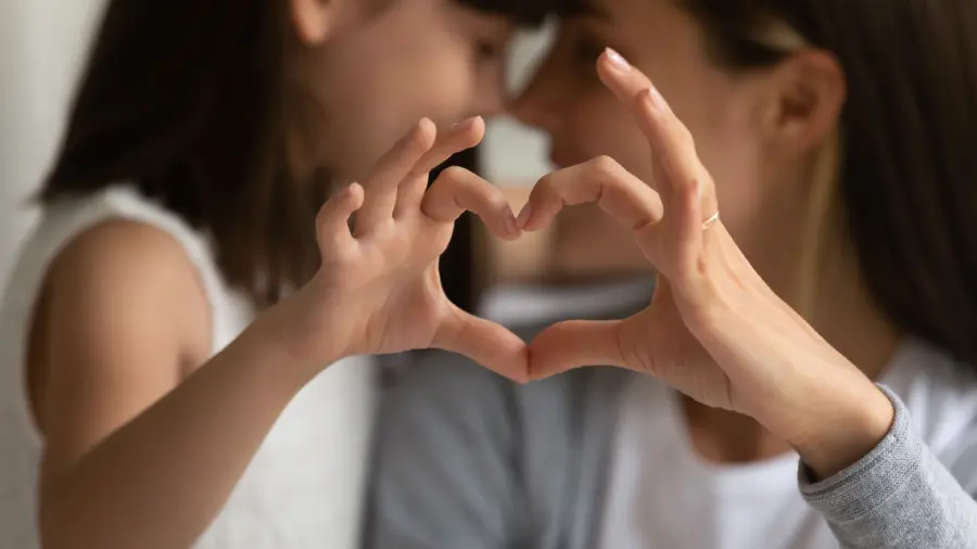 Close up of mother and little daughter make heart sign