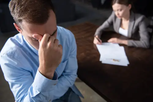 sad and upset man and woman couple signing divorce documents at table